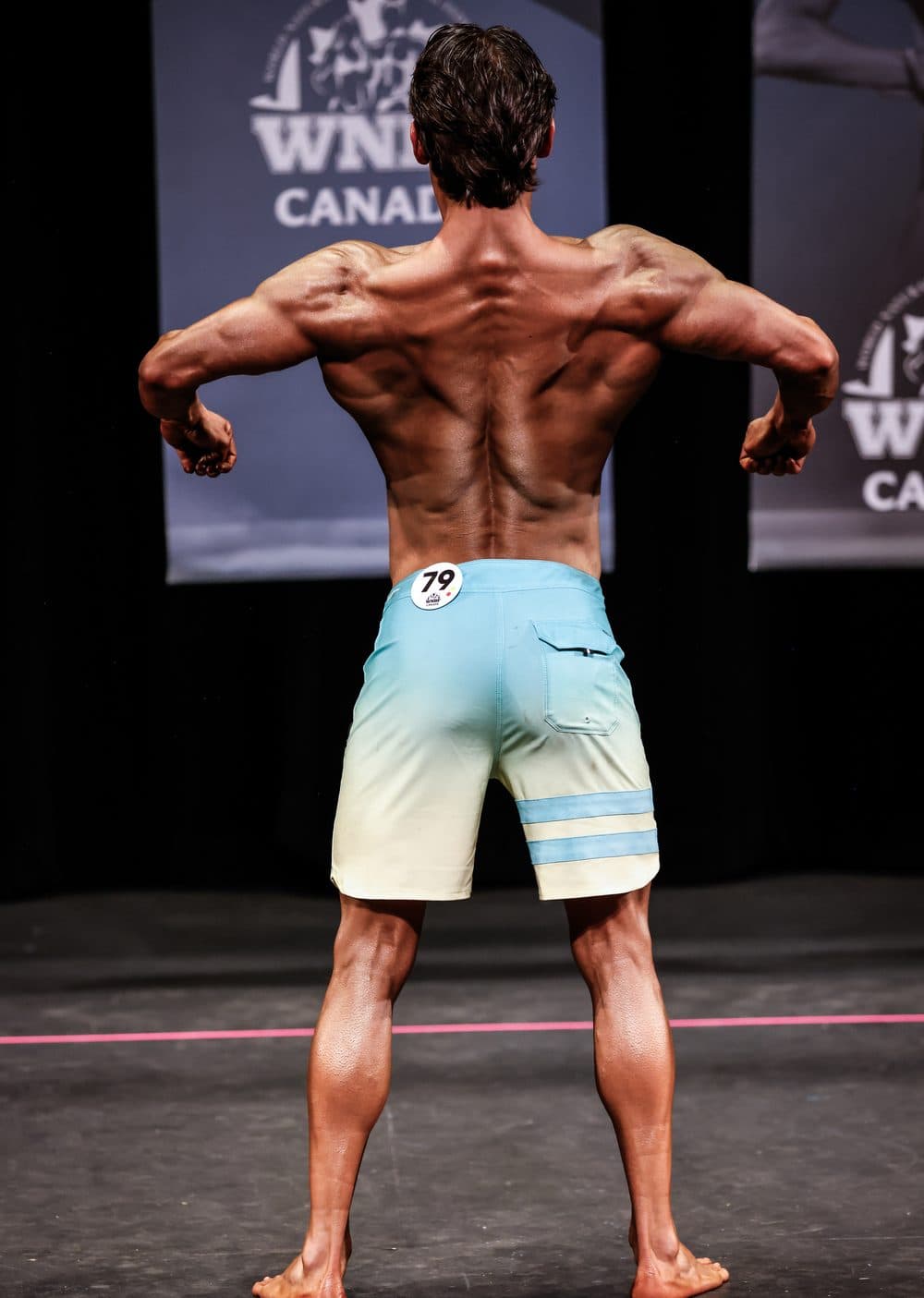 Celal in a rear pose on stage at WNBF Canada