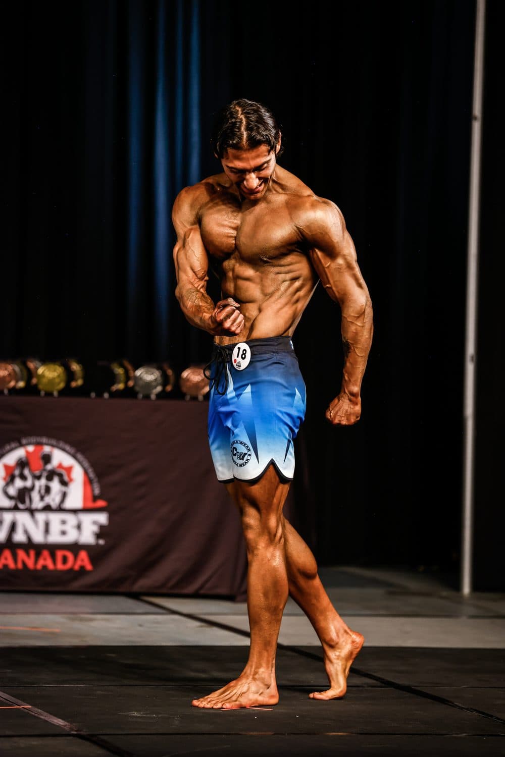 Celal posing on stage at a WNBF Canada show